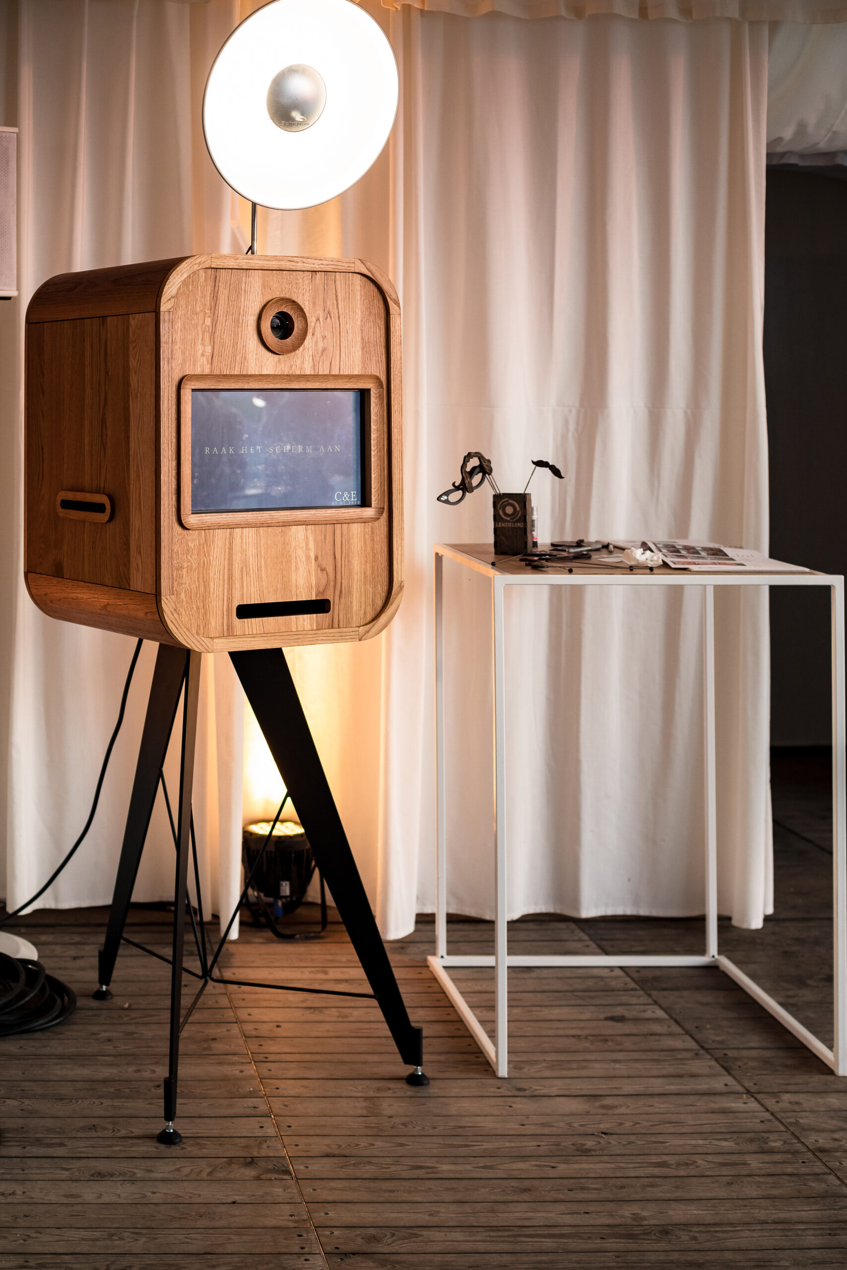 Vintage-stijl houten fotohokje op zwarte poten met ronde lamp in Brugge, gefotografeerd door een fotograaf gespecialiseerd in trouw- en familiefotografie uit West-Vlaanderen.